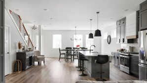 A modern kitchen with a central island, bar stools, and stainless steel appliances. - The Linden Home - Fountain Square Indianapolis (Indianapolis)