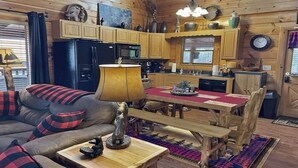 Un intérieur de chalet chaleureux comprenant un salon, une table à manger en bois et un coin cuisine.
