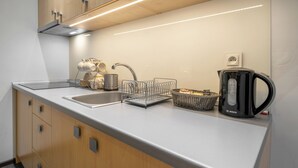 Una cocina moderna con un lavamanos de acero inoxidable, un hervidor Bosch y una cesta de pan en la encimera.