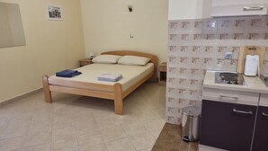 A bedroom with a wooden bed, a nightstand, a wall-mounted air conditioner, and a small bedside table with a lamp. - Apartments Željka - Studio Apartment with Terrace (Orebic)