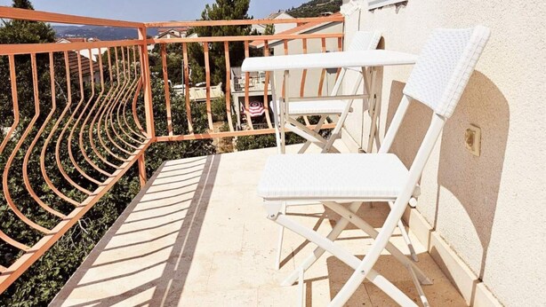 A balcony with a white chair, a small table, and a metal railing. - Apartments Željka - Studio Apartment with Terrace (Orebic)