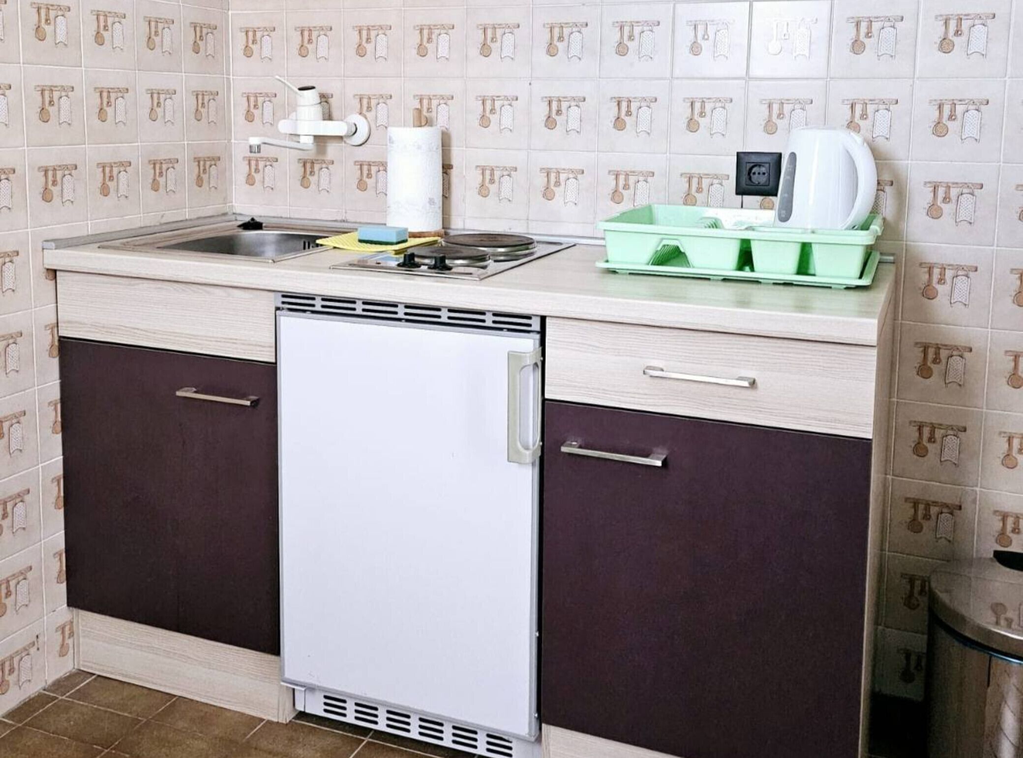 Eine kleine Küche mit eingebautem Kühlschrank, einer Spüle und einer Arbeitsfläche.