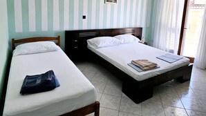 A room with two beds, a wooden headboard, a tiled floor, and a window with curtains. - Apartments Željka - Studio Apartment with Terrace (Orebic)