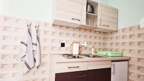 A compact kitchen with a sink, a stove, and a refrigerator. There are cabinets above the counter and a towel hanging on the wall. - Apartments Željka - Studio Apartment with Terrace (Orebic)