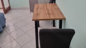 A dining table with four chairs, a tiled floor, and a door in the background. - Apartments Željka - Studio Apartment with Terrace (Orebic)