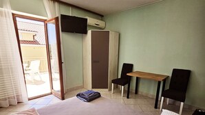 Une chambre d’hôtel équipée d’un lit, d’un bureau, de deux chaises, d’une télévision et d’un appareil de climatisation.