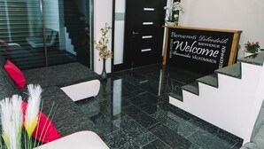 A modern reception area with a black reception desk, a welcome sign, and a sofa with decorative pillows.