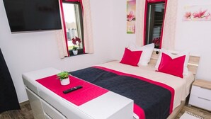 A bedroom with a bed, bedside tables, a desk, and a TV.