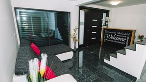 A modern reception area with a black reception desk, a welcome sign, and a sofa with decorative pillows.