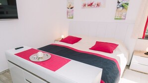 A modern bedroom with a bed, bedside tables, a TV, and artwork on the wall.