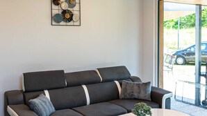 A modern living room with a dark grey sofa, a round coffee table, and a decorative wall piece.