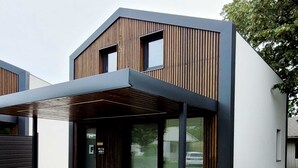 A modern two-story building with a wooden facade and a covered outdoor seating area.