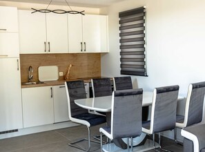 Una cocina moderna con armarios blancos, encimera de madera y una zona de comedor con una mesa redonda y cuatro sillas.