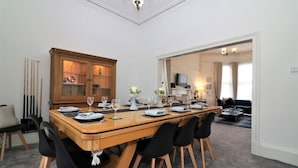 A dining area with a wooden table set for six, black chairs, a wooden cabinet with glass doors, and a chandelier. - Private 10 Bedrooms Detached Villa in Glasgow | Pool Table | Garden | Piano (Glasgow)