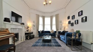 A living room with a piano, sofas, a coffee table, and a fireplace. - Private 10 Bedrooms Detached Villa in Glasgow | Pool Table | Garden | Piano (Glasgow)