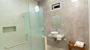 A modern bathroom with a glass shower enclosure, a sink with a mirror, and a wooden chair. - Edificio La Esquina Cesar Mariscos (Tela)