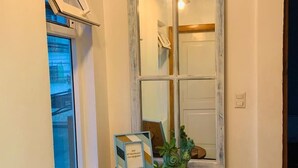 A hallway with a window, a small table with a picture frame, and a mirror. - Edificio La Esquina Cesar Mariscos (Tela)