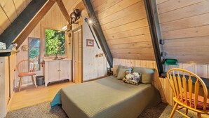 Un dormitorio acogedor en el ático, con cama, una silla y un pequeño escritorio.