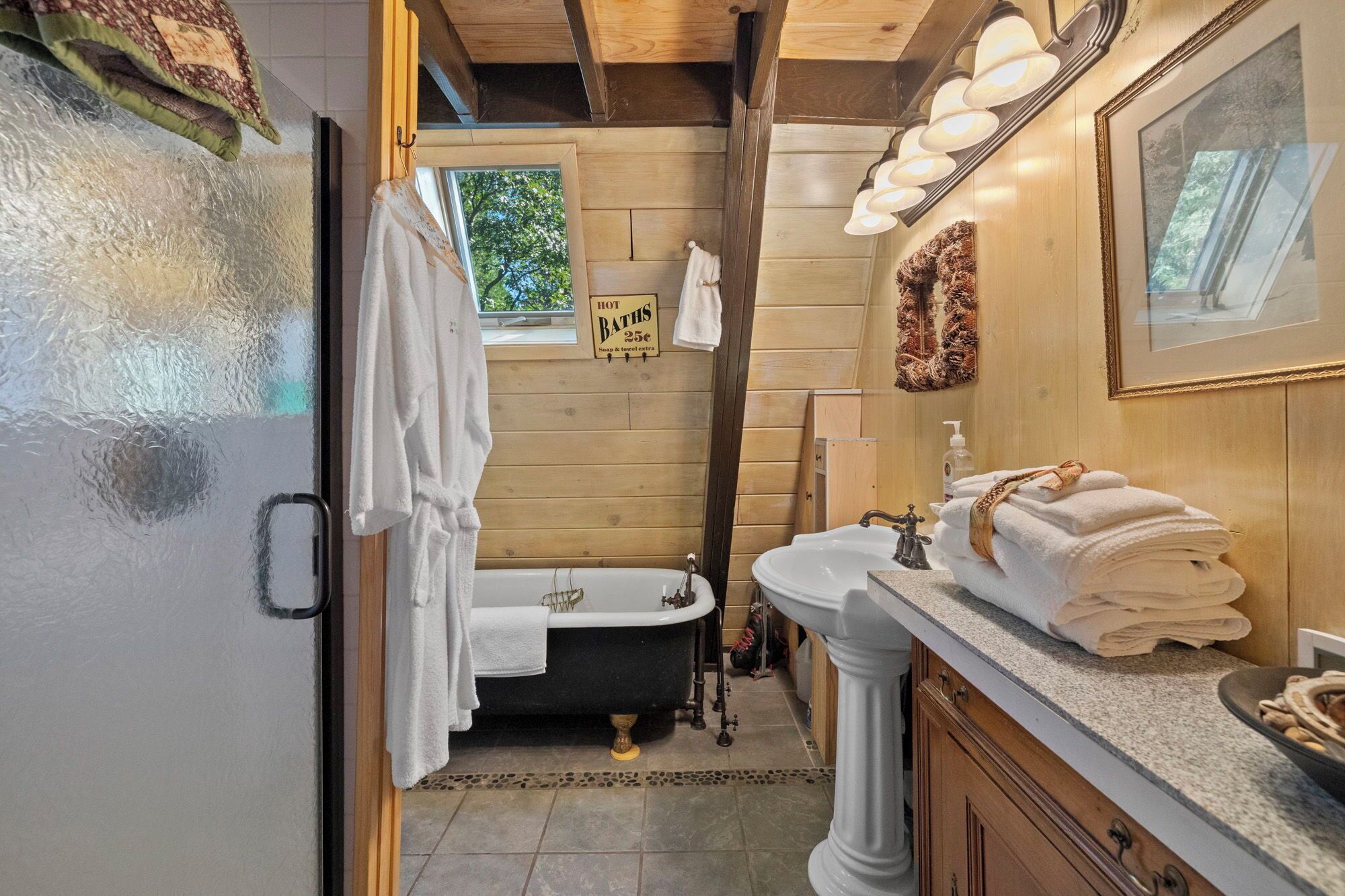 A bathroom with a bathtub, a sink, and a mirror. There is a sign above the bathtub that reads "HOT BATHS 25c".