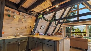 Una cocina moderna con muebles de madera, una isla central y un comedor con vistas al exterior.