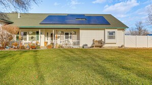Ein Haus mit Solardach, einer Veranda mit Bank und einem umzäunten Garten.