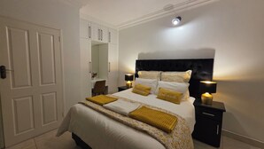 A neatly arranged bedroom with a bed, bedside lamps, a nightstand, and a wardrobe.