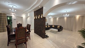 A spacious living room with a dining area, a brick accent wall, and a curved seating arrangement.