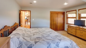Un dormitorio con cama, armario de madera, cómoda y televisor.