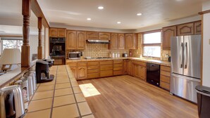 A spacious kitchen with wooden cabinets, a stainless steel refrigerator, and a tiled backsplash. - Mtn-View Retreat Near Hiking in Bayfield! (Bayfield)