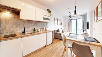 Una cocina moderna con horno empotrado, un lavamanos y un comedor con mesa y sillas.