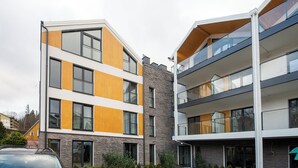 A modern multi-story residential building with balconies, large windows, and a mix of stone and wood facade materials. - RentPlanet - Apartament Belle View (Szklarska Poreba)