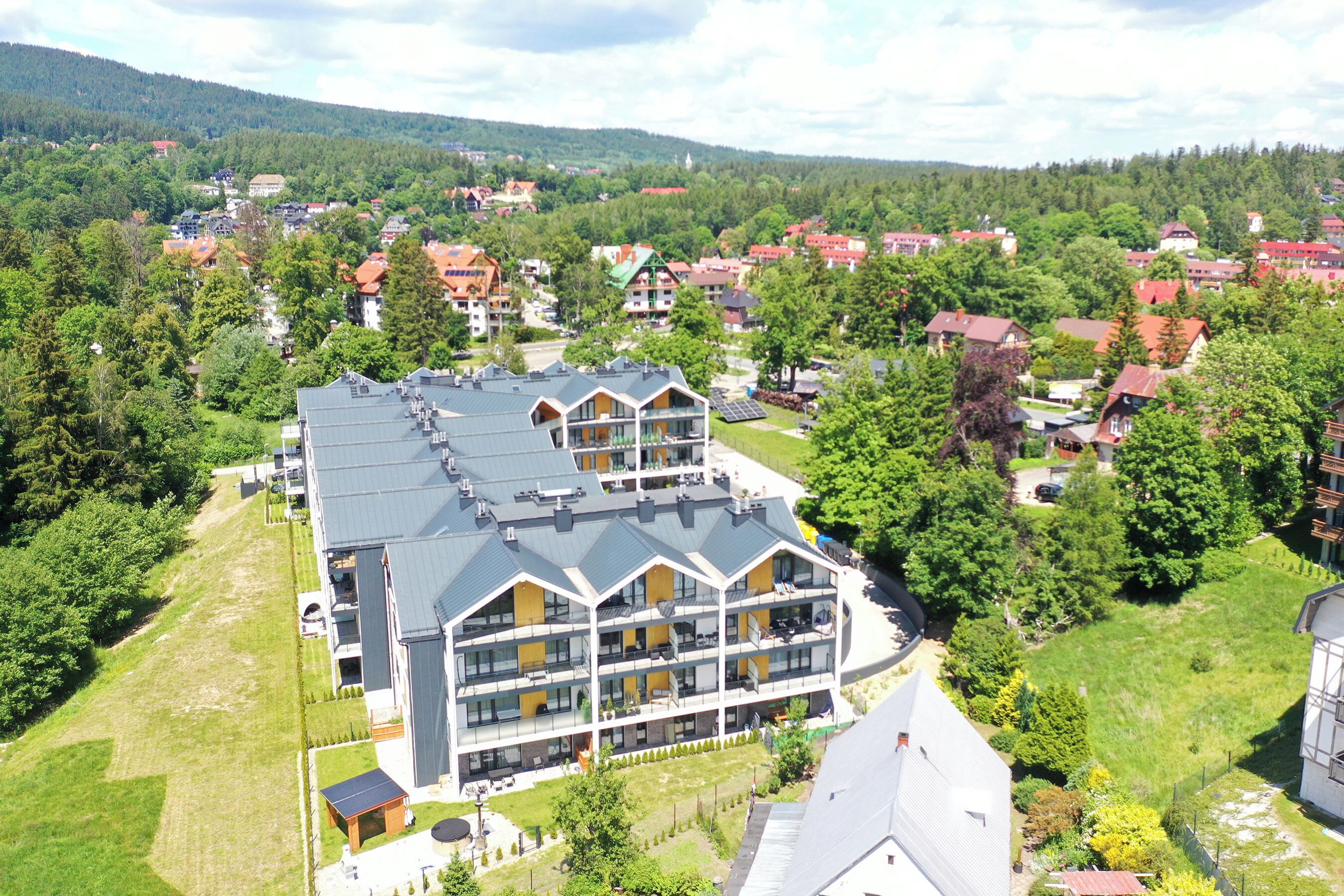 A multi-story hotel with a flat roof and a large outdoor area with a pool.