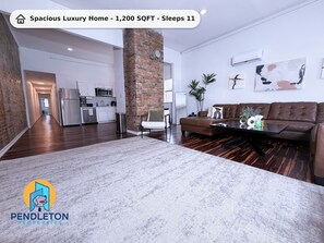 A spacious luxury home with a modern kitchen, a living area with a brown leather sofa, and a large rug. - City Luxury @ Smart Pricing + Parking + Family-Friendly (Cincinnati)