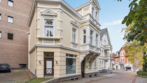 A corner building with a beige facade, large windows, and a visible entrance. - Stylish Studio · Augustaplatz · Kurpark · GOP (Bad Oeynhausen)