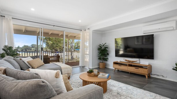 A modern living room with a large TV, comfortable seating, and a view to the outside.