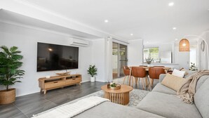 A modern living room with a flat-screen TV, wooden entertainment unit, and a sofa.
