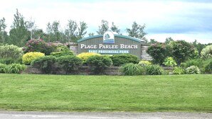 A sign for 'Plage Parlee Beach Park Provincial Park' with a stone wall and landscaped garden in front. - Spacious Beachside Chalet is just minutes walk to Parlee Beach (Pointe-du-Chêne)
