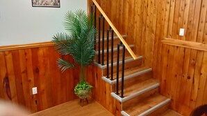 A wooden staircase with a handrail, a potted plant, and a framed picture on the wall. - Spacious Beachside Chalet is just minutes walk to Parlee Beach (Pointe-du-Chêne)