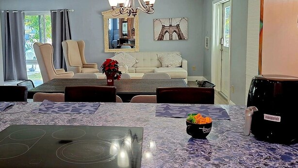 A dining area with a table set for four, a sofa, and a chandelier. - Private duplex house with WI-FI, TVs, BBQ Parking ,enjoy a peaceful Getaway (Cutler)