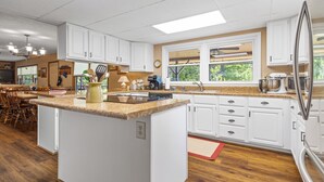 Una cocina amplia con armarios blancos, encimera de granito y una isla grande.