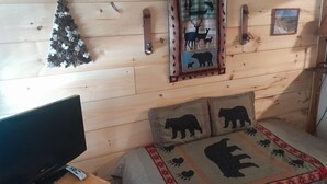 Une chambre confortable dans un chalet, avec un lit, une télévision et un cadre photo fixé au mur.