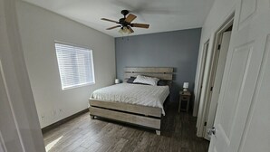 A bedroom with a bed, a ceiling fan, a nightstand, and a window with blinds. - Cozy spacious modern guest house in charming Queen Creek with AC & WiFi (Queen Creek)