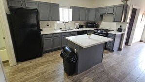 A modern kitchen with grey cabinets, a black refrigerator, a white countertop island, and a stainless steel stove. - Cozy spacious modern guest house in charming Queen Creek with AC & WiFi (Queen Creek)