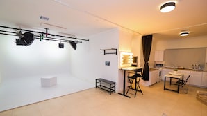 Um espaço de estar moderno com cozinha compacta, área de jantar e um pequeno espaço de convívio com mesa e cadeiras.
