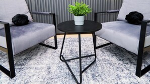Uma área de estar com duas cadeiras e uma mesinha com uma planta.