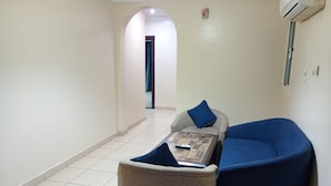 A small, private sitting area with a sofa and armchair, a small table, and a remote control on the table. - Asalat Alhamra (Jeddah)