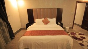 A large bed with a headboard, two bedside tables, and a rug. - Asalat Alhamra (Jeddah)