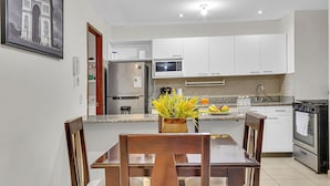 A modern kitchen with white cabinets, a built-in microwave, and a stainless steel refrigerator.