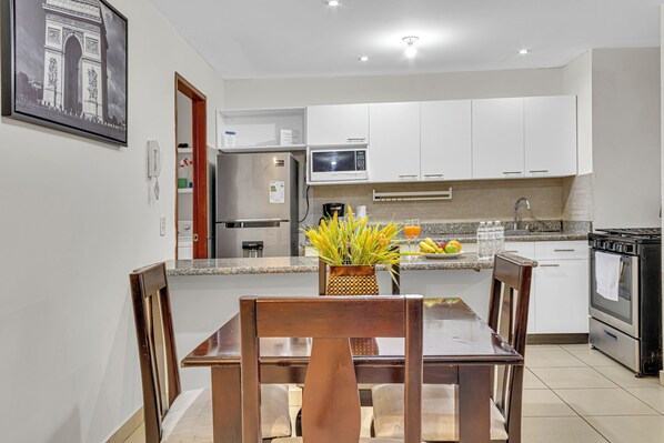 Enjoy meals in this well-appointed kitchen and dining area, featuring a dining table for four, a refrigerator, microwave, and stove.
