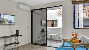A hotel room with a desk, a computer, a sliding glass door to a balcony, and a tray with fruit and juice.